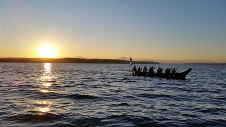 The Confederated Tribes of Coos, Lower Umpqua, and Siuslaw Indians members in canoe on water at sunset