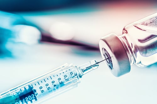 close up of syringe pulling vaccine from vial