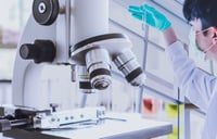 microscope and scientist looking at test tube