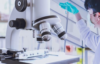 microscope and scientist looking at test tube