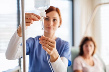 Nurse with IV bag and patient in the background