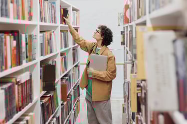 Person reaching for book on library shelf