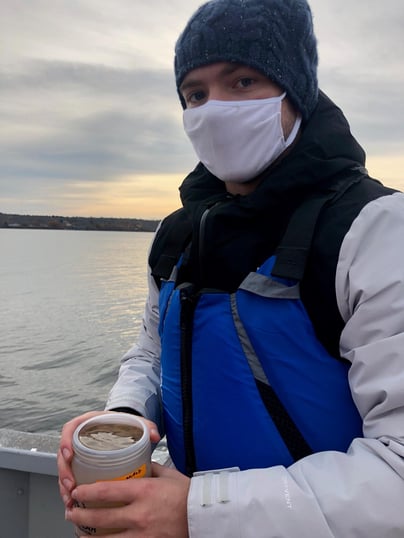 Maine Maritime Academy student holding the end of a plankton net containing a sample