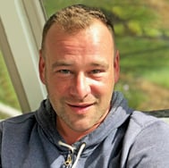 Headshot of man with hoodie in front of window