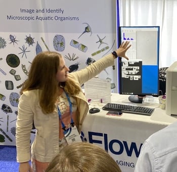 Woman at trade show presenting, pointing to screen