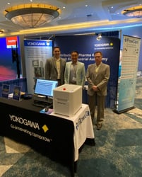 3 men in Yokogawa trade show booth with FlowCam