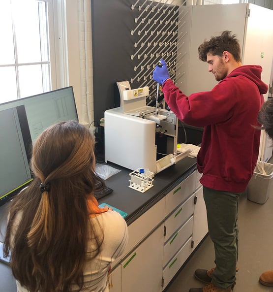 Bates student pipetting sample into FlowCam, watched by instructor