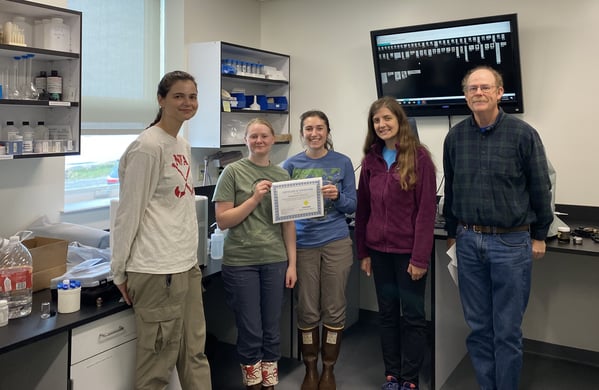 Professor with students in lab holding FlowCam training certificate