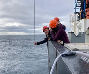 woman smiling as she holds line submerged for zooplankton sample collection