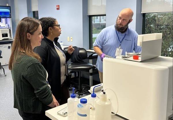 FlowCam scientist demonstrating instrument in lab to two other people
