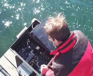 Man bent over early FlowCam prototype over water