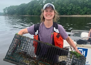 Young woman in boat holding crab trap