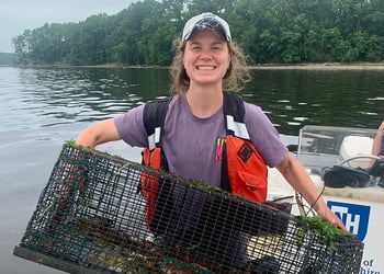 Kelsey Meyer in boat holding crab trap