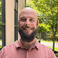 Headshot of man with beard in red shirt