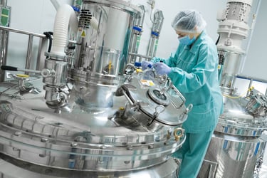 Worker in PPE using a large bioreactor