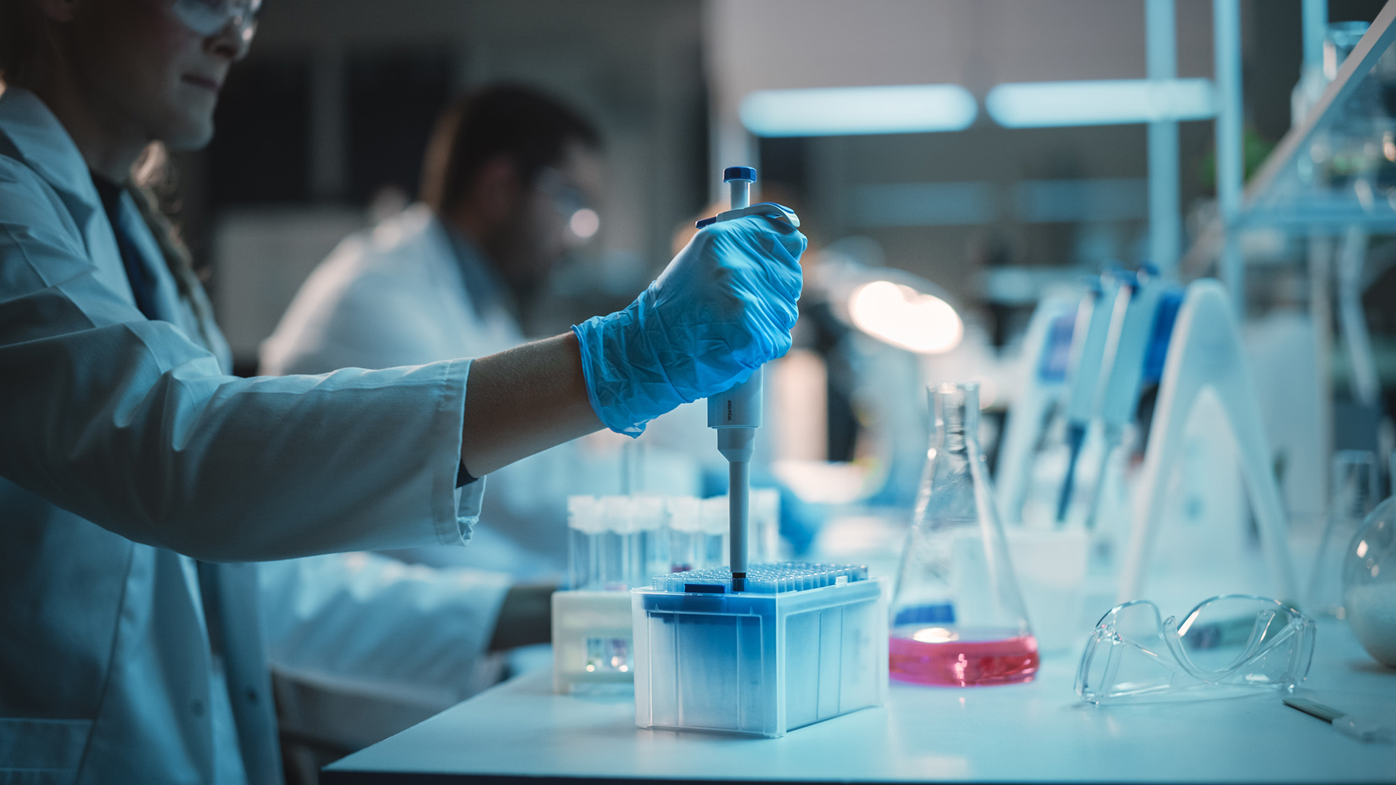 Stock photo of scientists in lab, taking sample from test tube