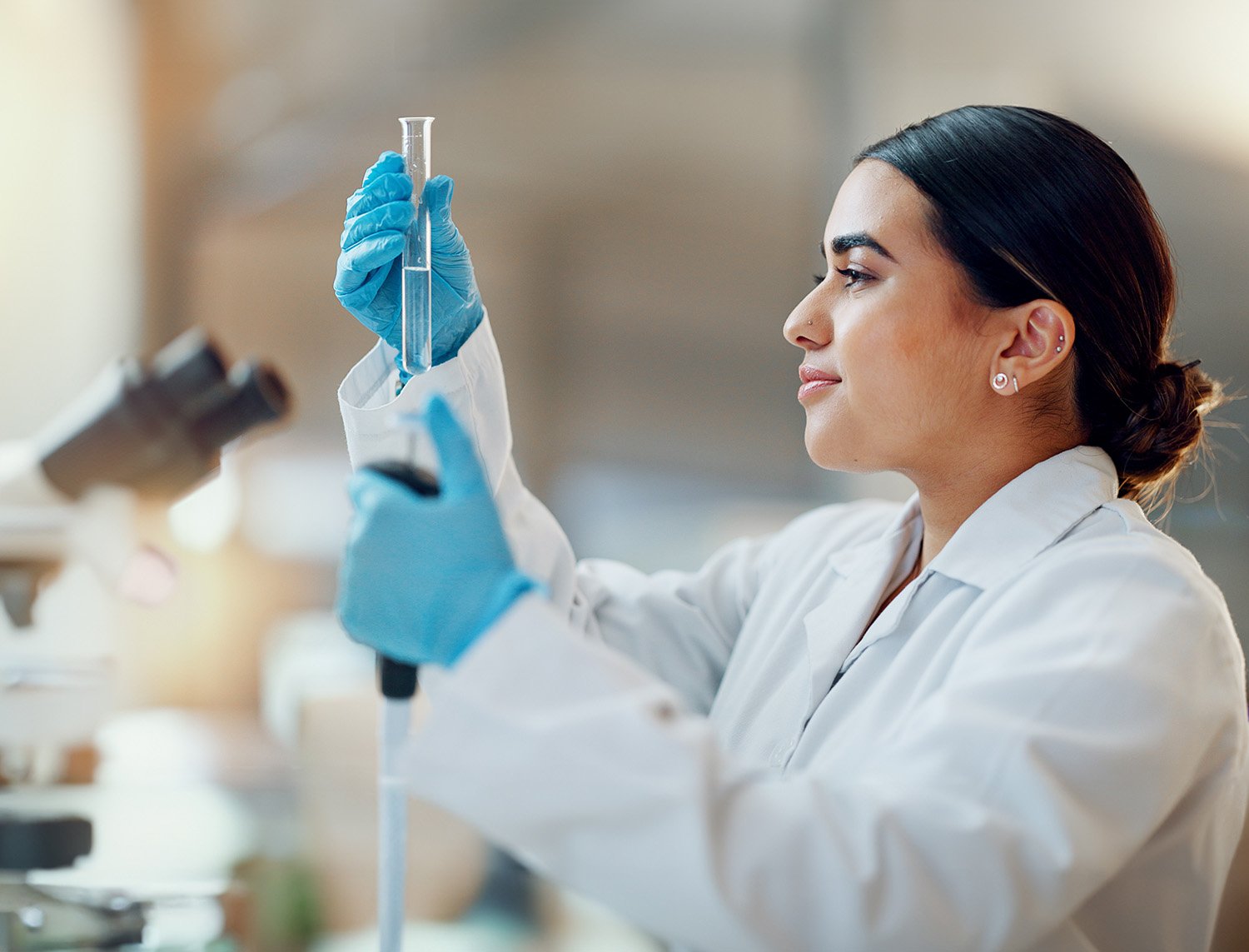 Scientist looking at test tube, holding pipetter
